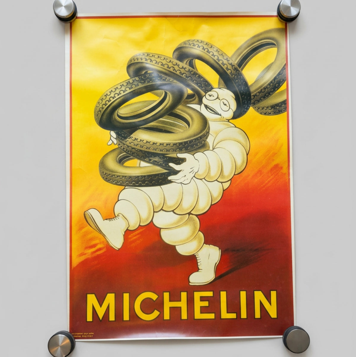 Une magnifique composition publicitaire Michelin mettant en scène Bibendum et ses pneus, dans un grand format de 98 × 68 cm.