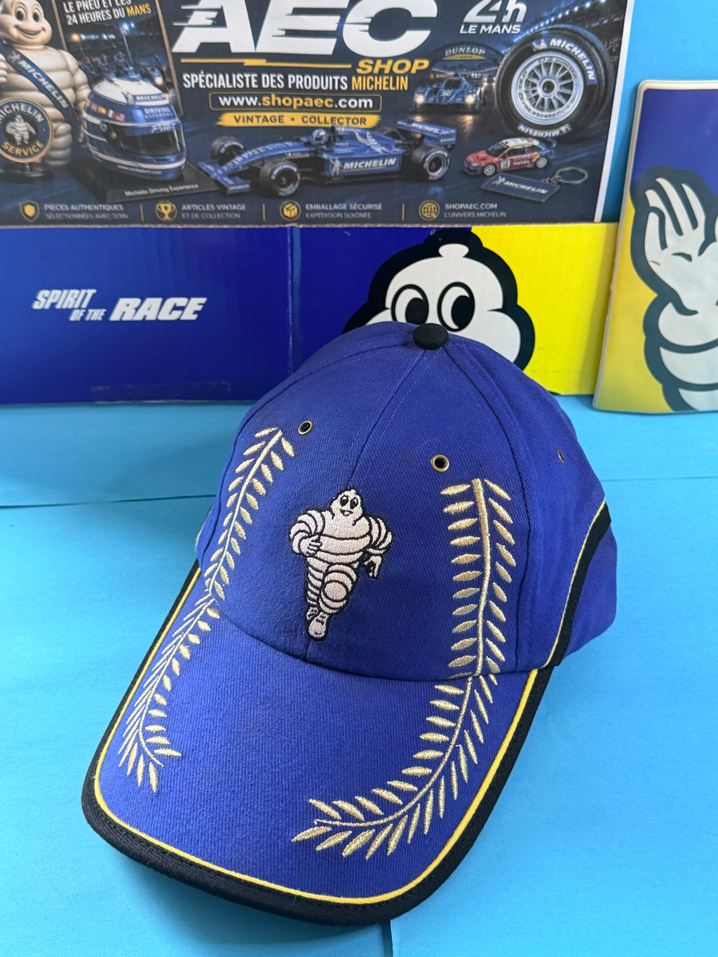 Vue de face de la casquette Michelin Podium collector avec Bibendum central, lauriers brodés et liseré jaune sur la visière.