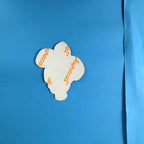 Verso de l'autocollant Bibendum Michelin avec papier protecteur adhésif portant des inscriptions orange, objet publicitaire en très bon état.