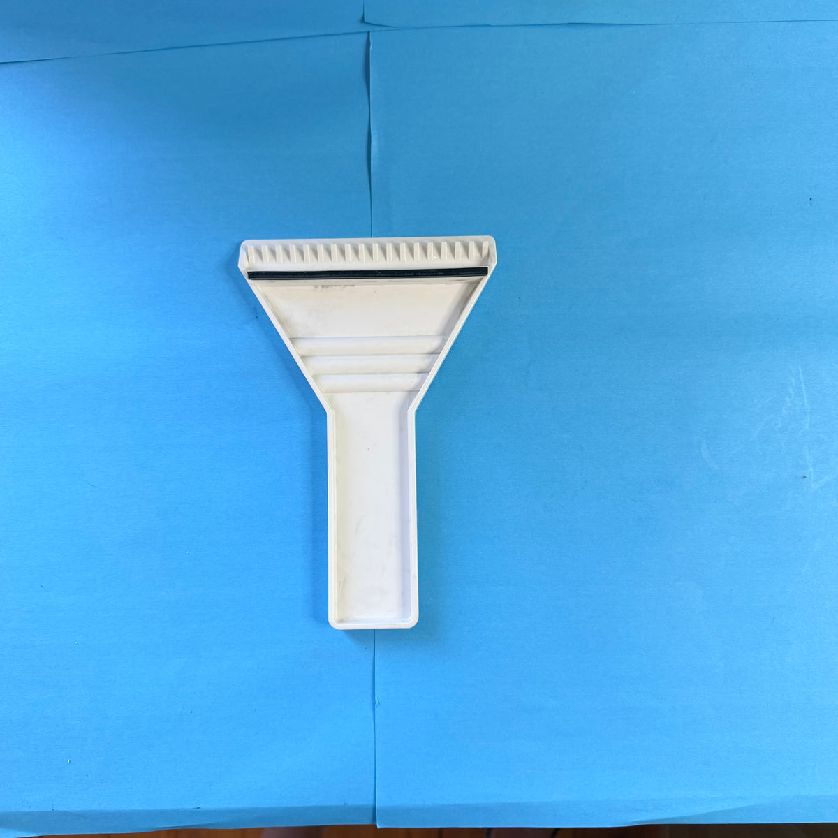 Vue arrière du gratte-pare-brise Michelin blanc, présentant sa structure nervurée, sa poignée ergonomique et sa bordure noire de raclage.