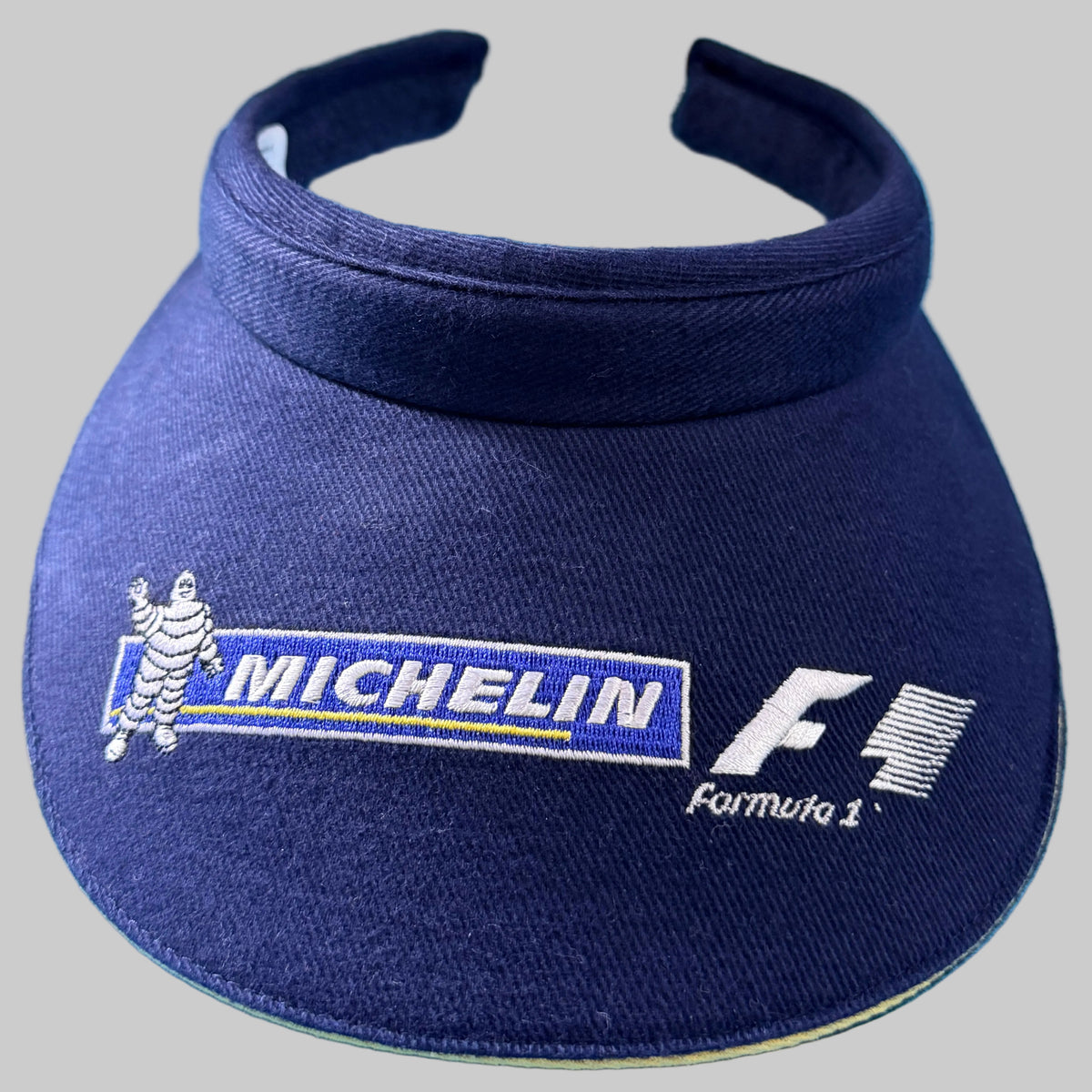 Visière Michelin Formula 1 bleu marine avec broderies Bibendum, Michelin et logo F1 vintage.