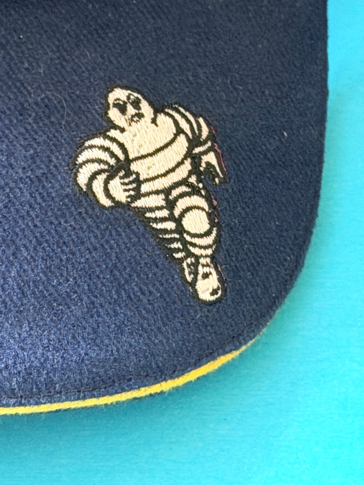 Gros plan sur le Bibendum Michelin brodé sur la visière bleu marine Formula 1.