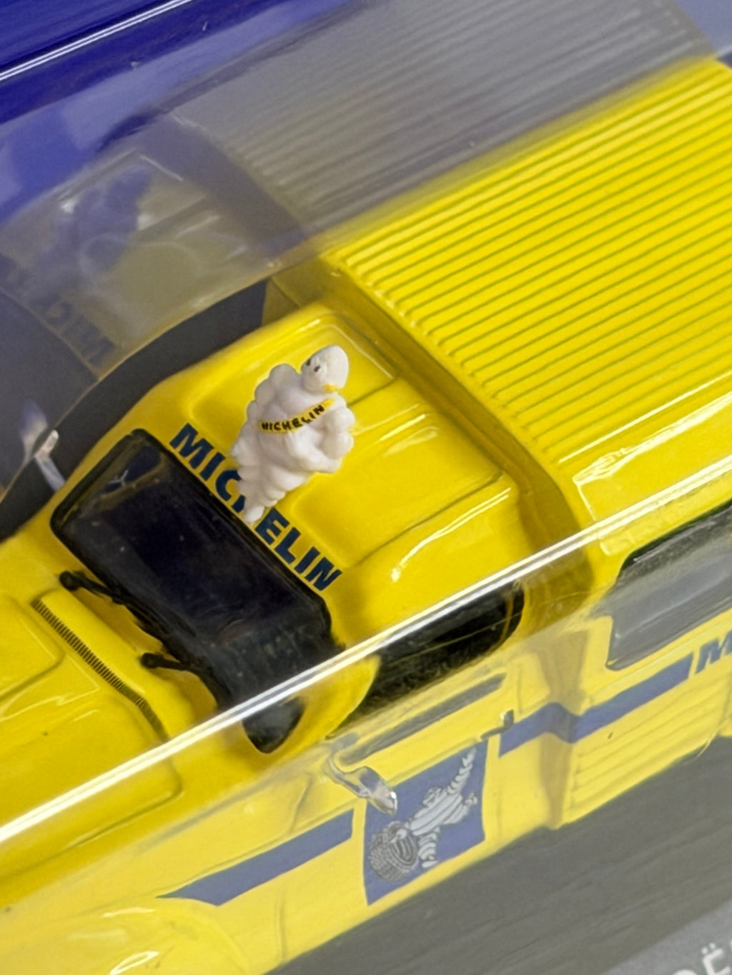 Vue rapprochée du coffret transparent de la Citroën Acadiane Michelin 1/43, avec détails de la carrosserie et de la décoration publicitaire.