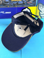 Vue intérieure de la casquette Michelin F1 Spirit of the Race neuve avec visière bleu marine bordée de jaune.