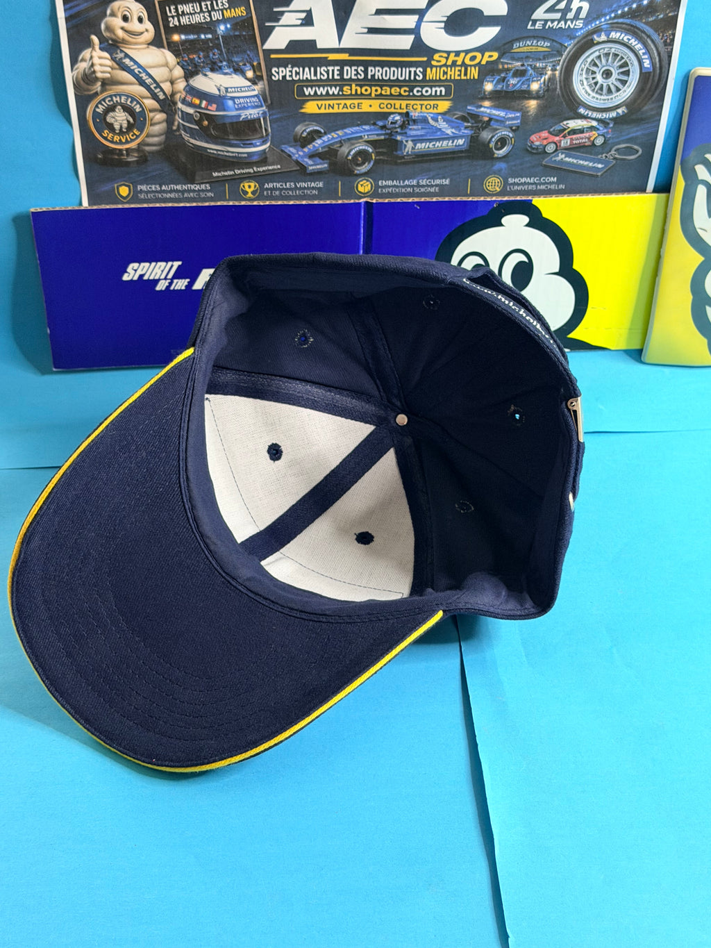 Vue intérieure de la casquette Michelin Formula 1 neuve bleu marine avec visière bordée de jaune et fermeture arrière réglable.