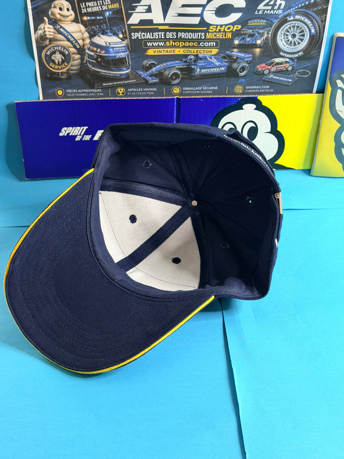 Vue intérieure de la casquette Michelin Formula 1 neuve bleu marine avec visière bordée de jaune et fermeture arrière réglable.