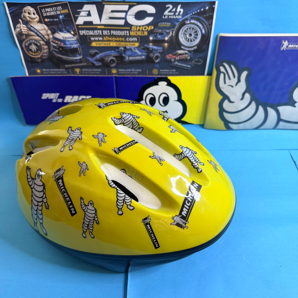 Casque Michelin Bibendum jaune brillant avec aérations et illustrations publicitaires, vue de côté.