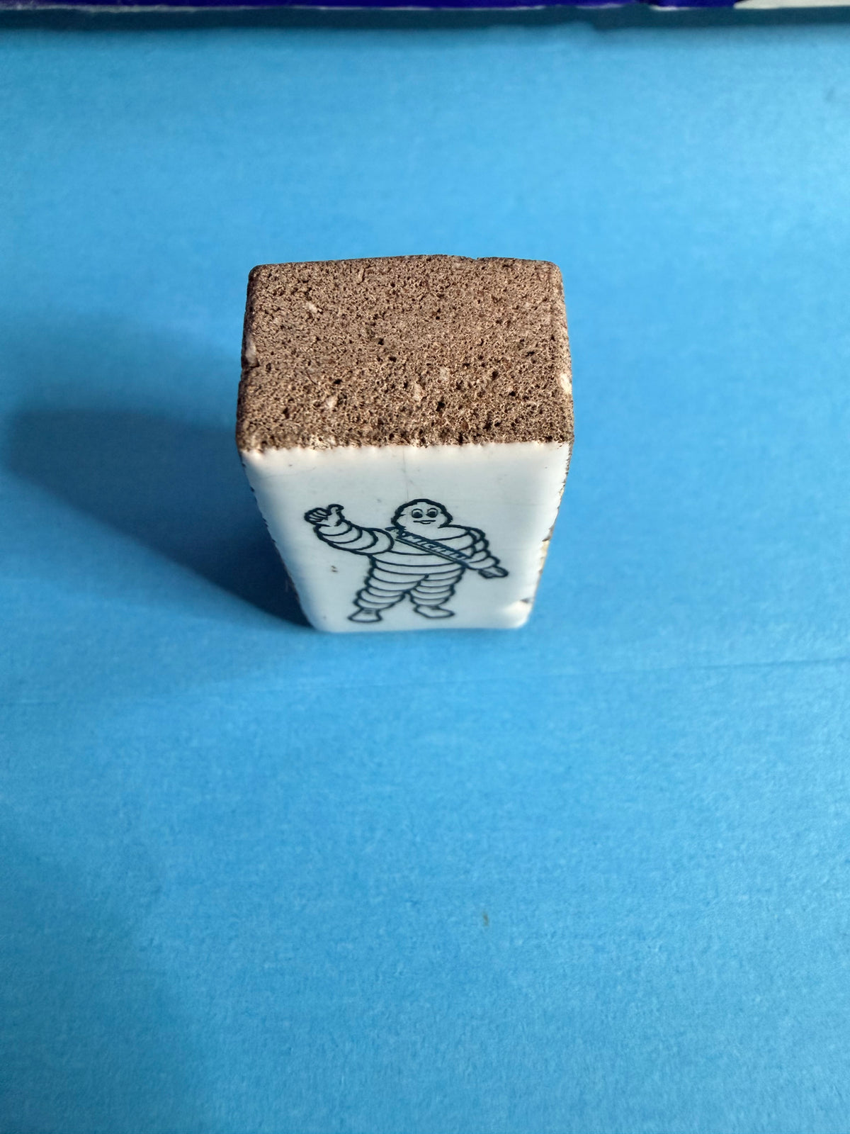 Vue de profil de la pièce Michelin Bibendum en faïence sur support minéral.